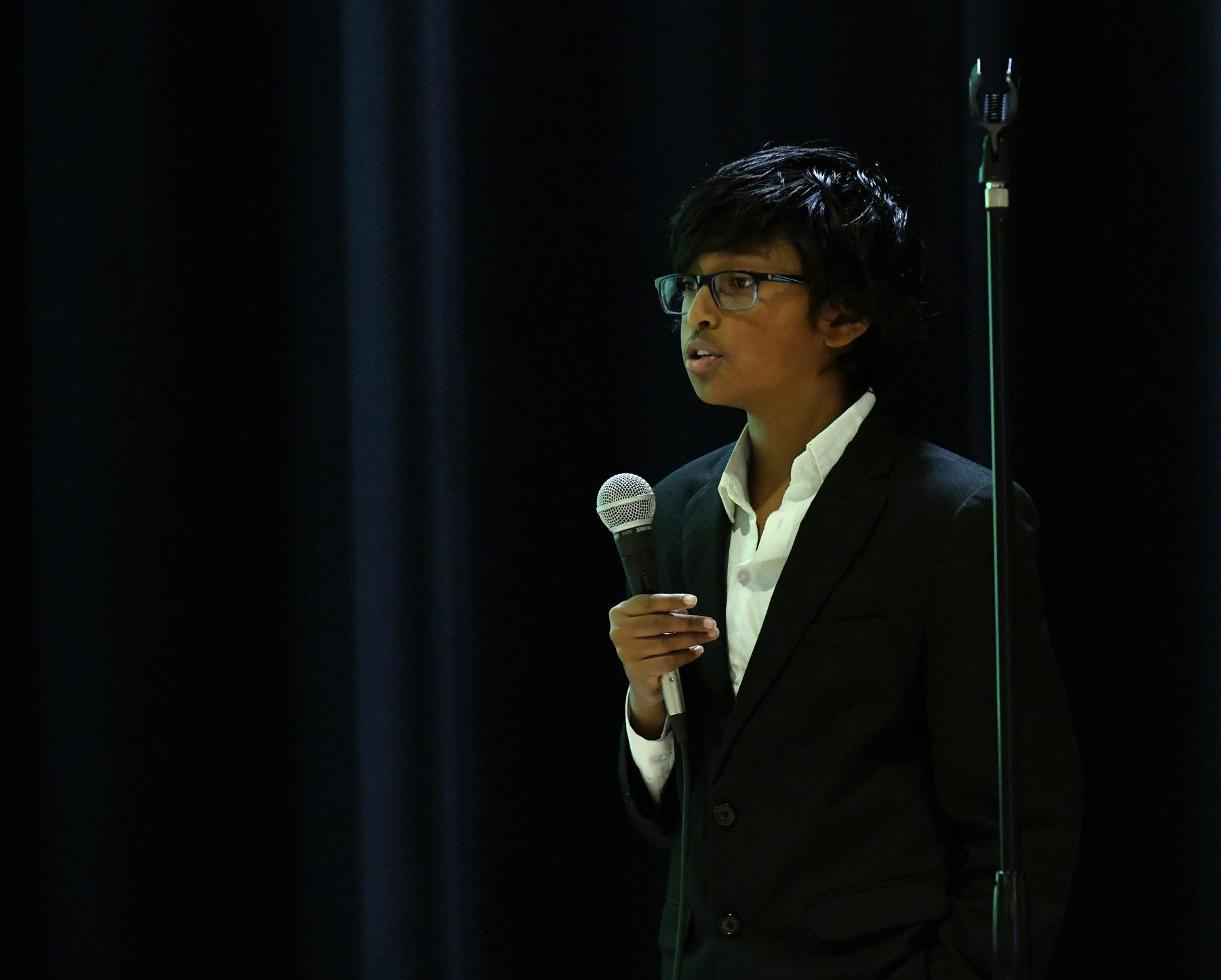 A Moody student speaking into a microphone during a debate event