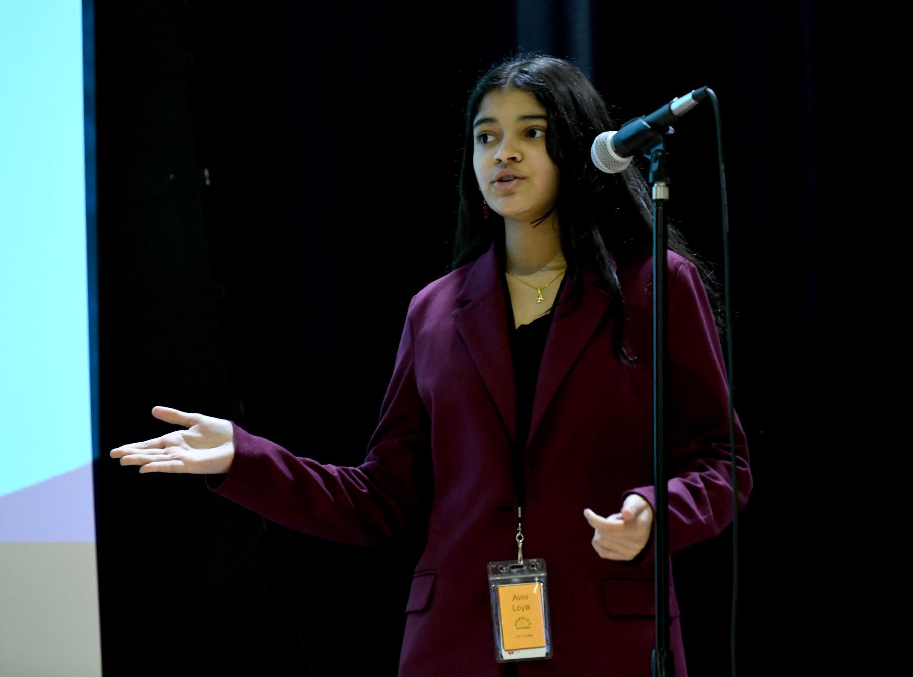 A Moody student delivering a speech at a microphone